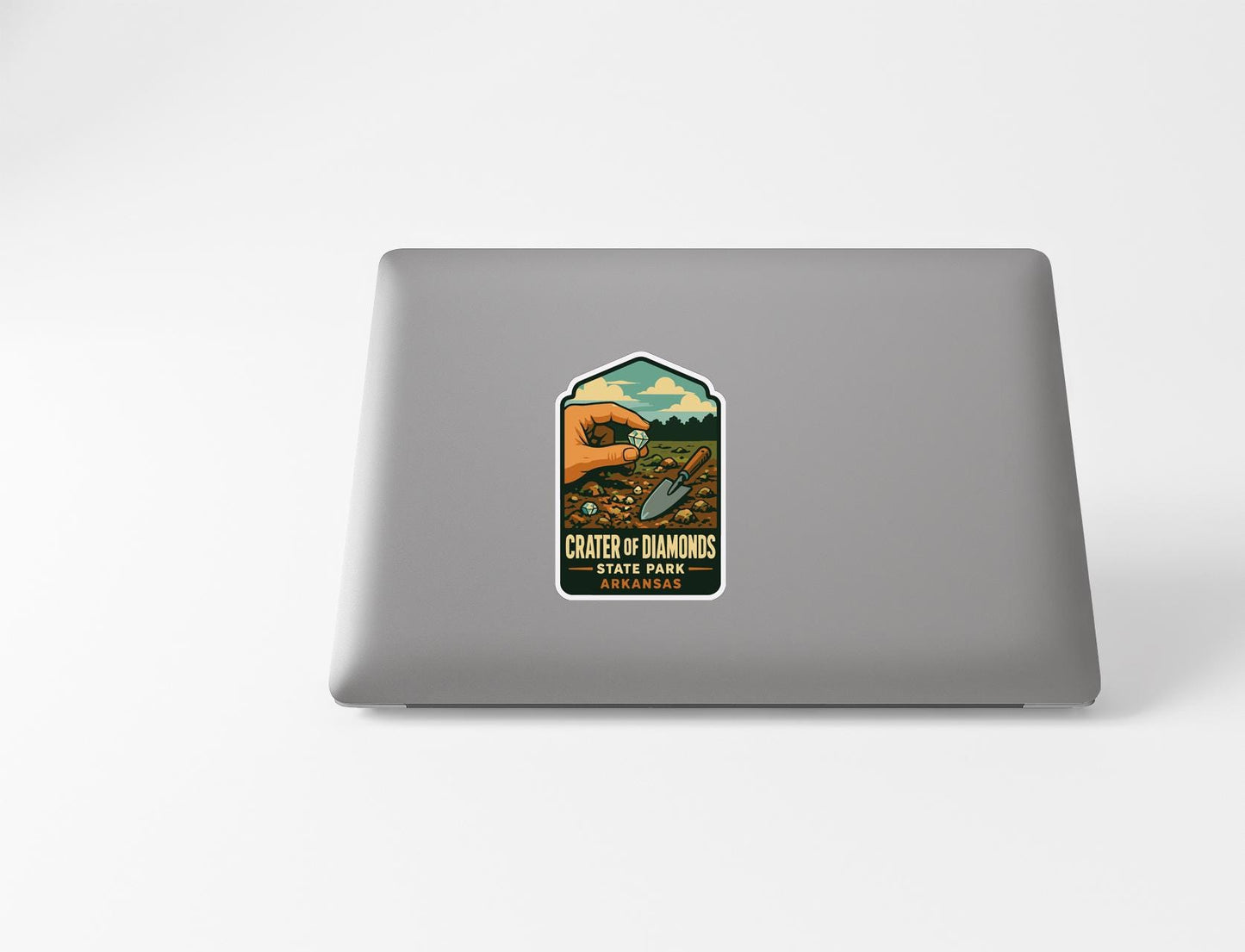 a sticker on a laptop with a vintage-style illustration of a hand holding a magnifying glass over a field of flowers.
