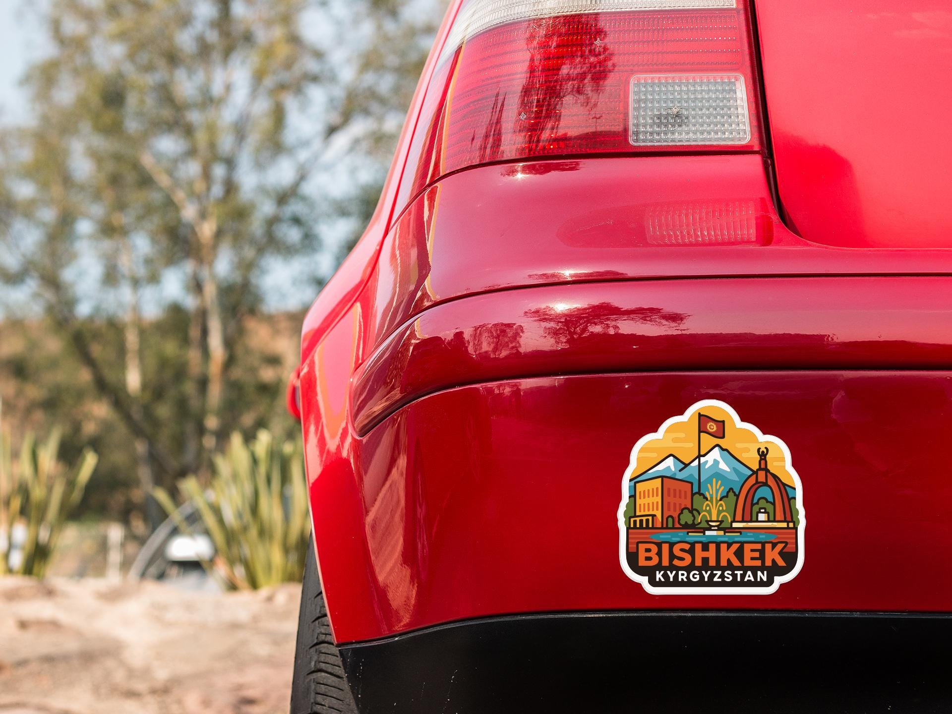 the rear end of a red car with a sticker on the trunk that says "BISHKÉ Kyrgyzstan".