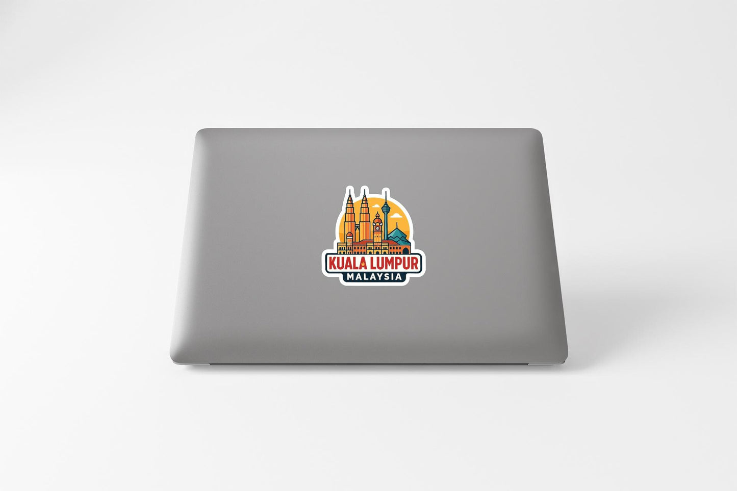 a sticker with an illustration of Kuala Lumpur, Malaysia, on the back of a laptop.