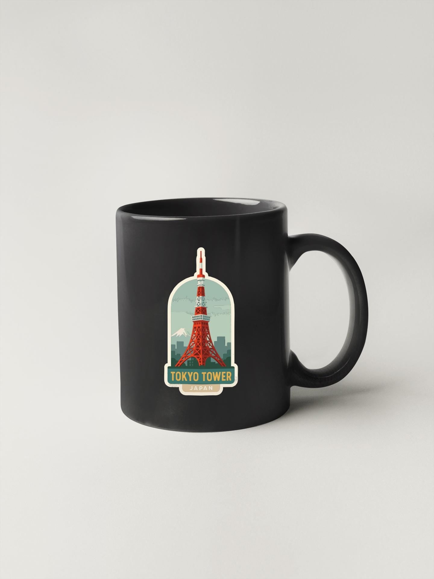 A black coffee mug with a sticker of the Tokyo Tower on it.