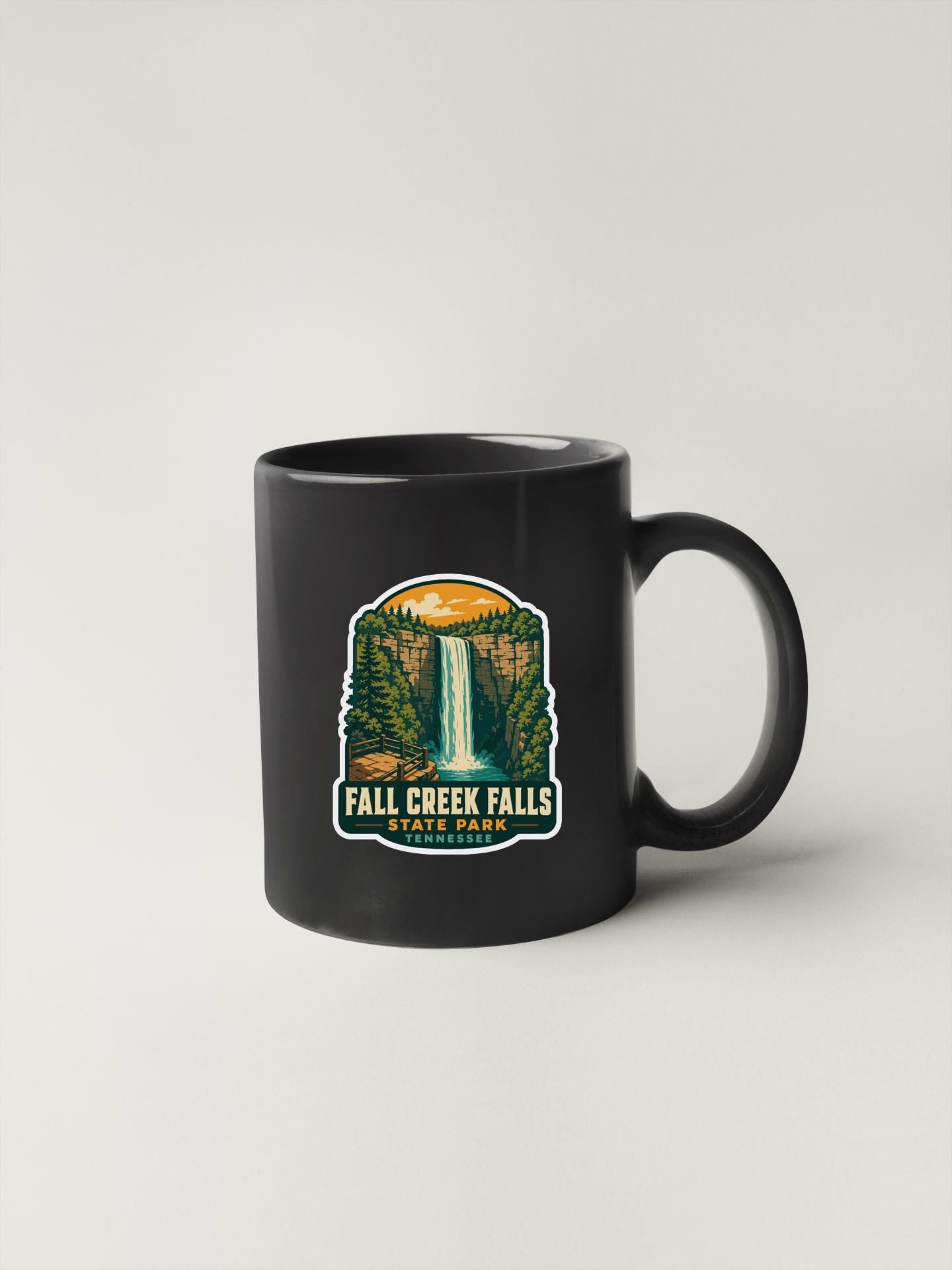 A black coffee mug with a graphic design depicting the falls of the Missouri River in Tennessee.