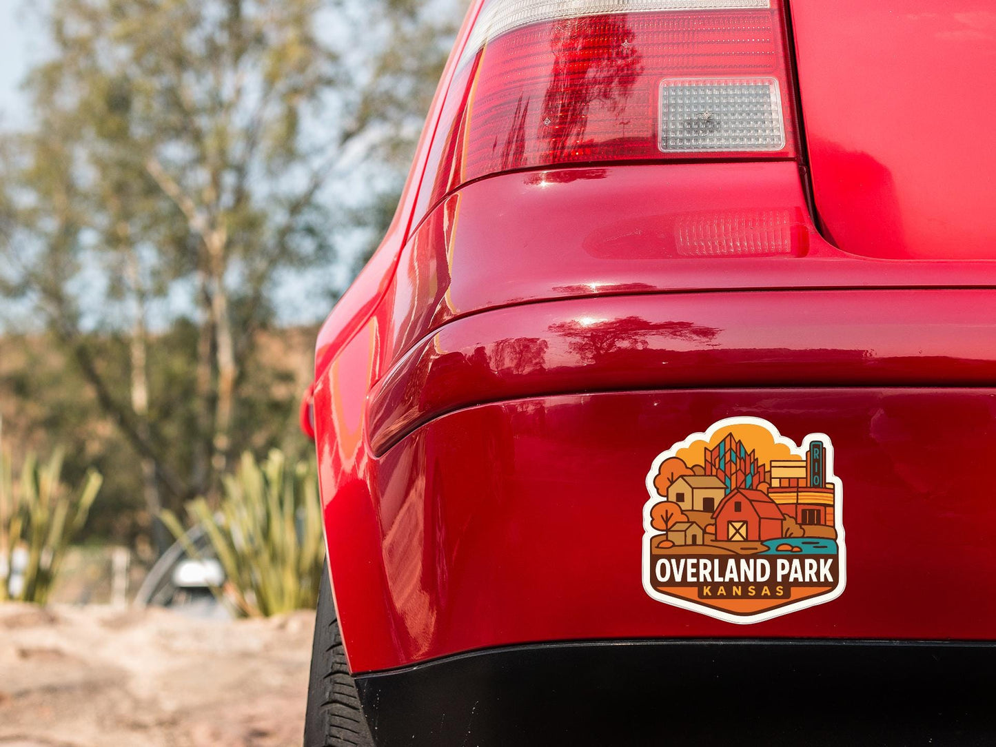 the rear end of a red car with a sticker on the trunk that says "Overland Park Kansas".