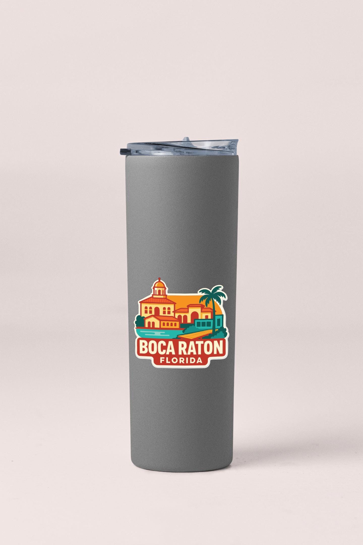 A gray insulated tumbler with a printed sticker depicting a tropical resort in Boca Raton, Florida.