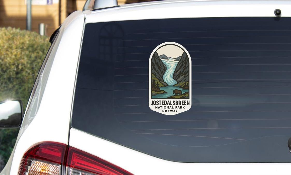 A sticker on the rear window of a car, depicting a scenic landscape with a waterfall and mountains.