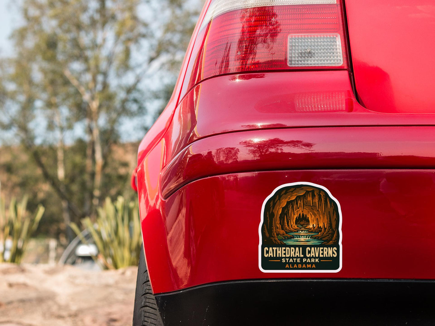 the rear end of a red car with a sticker on the back window that reads "CATHEDRAL CAVENS STATE PARK ALABAMA".