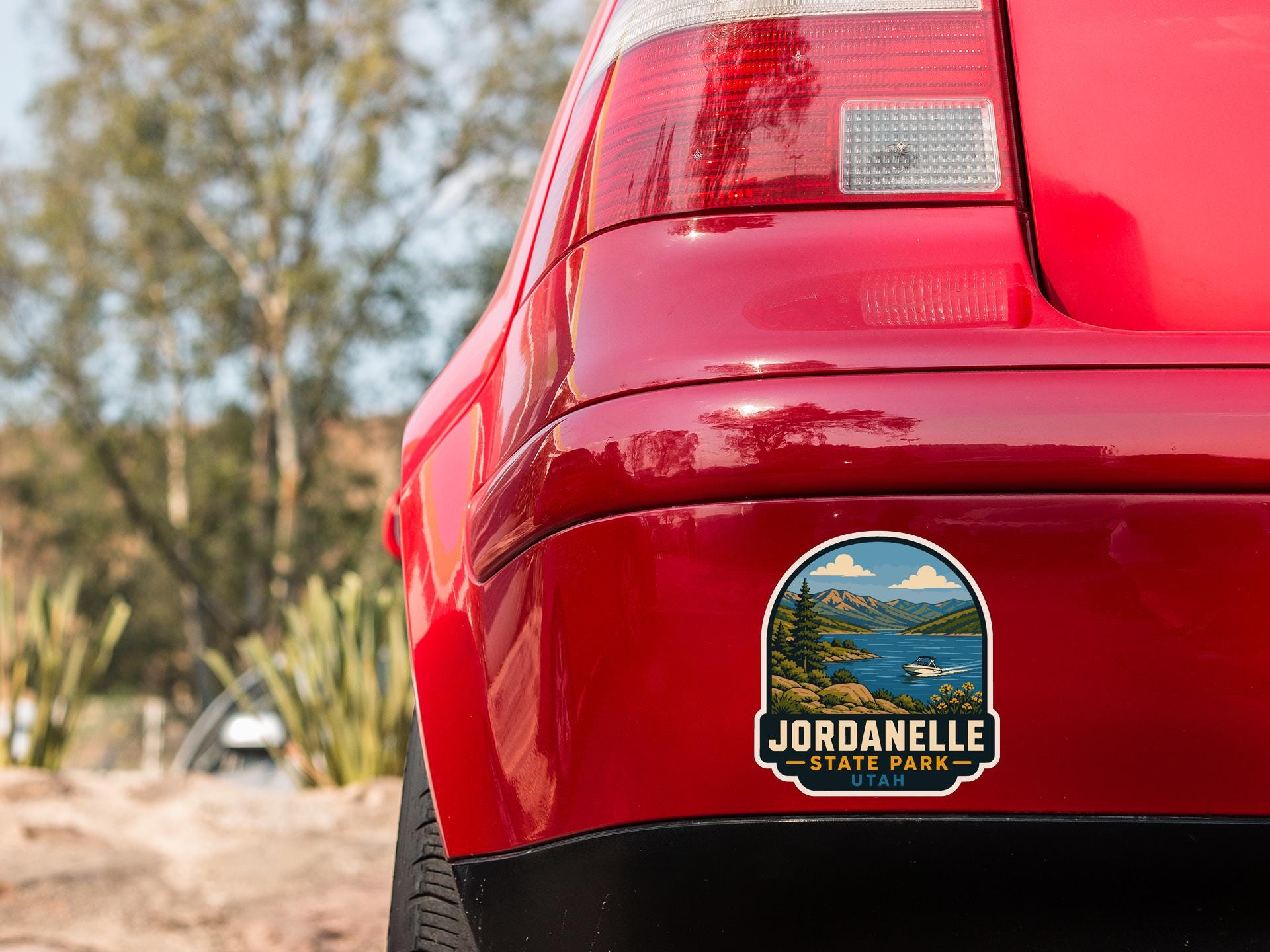 the rear end of a red car with a sticker on the back window that says "JORDANELLE STATE PARK - UTA".