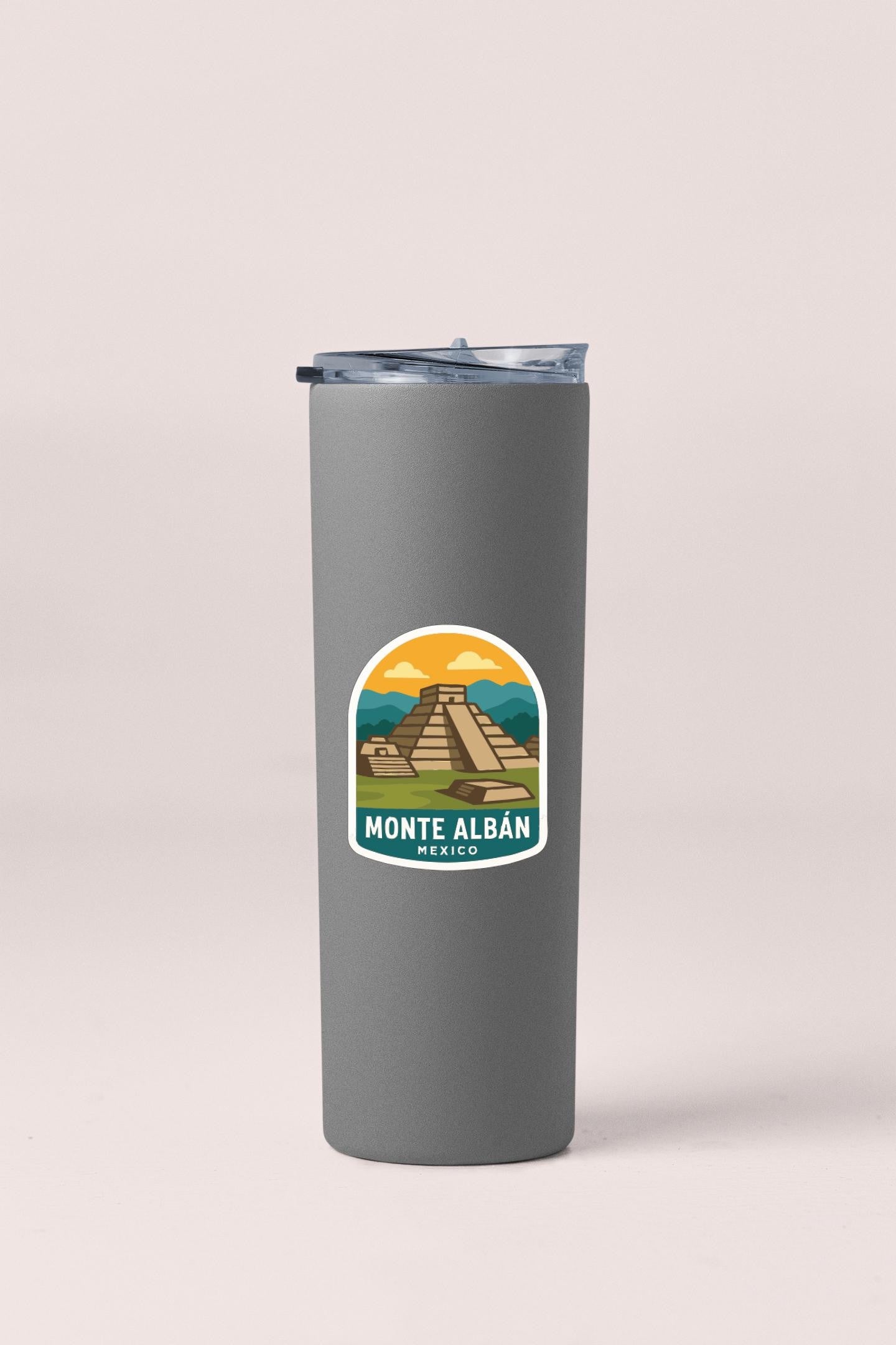 A gray insulated tumbler with a sticker depicting the Mayan pyramid of Monte Albán, a famous landmark in Mexico.