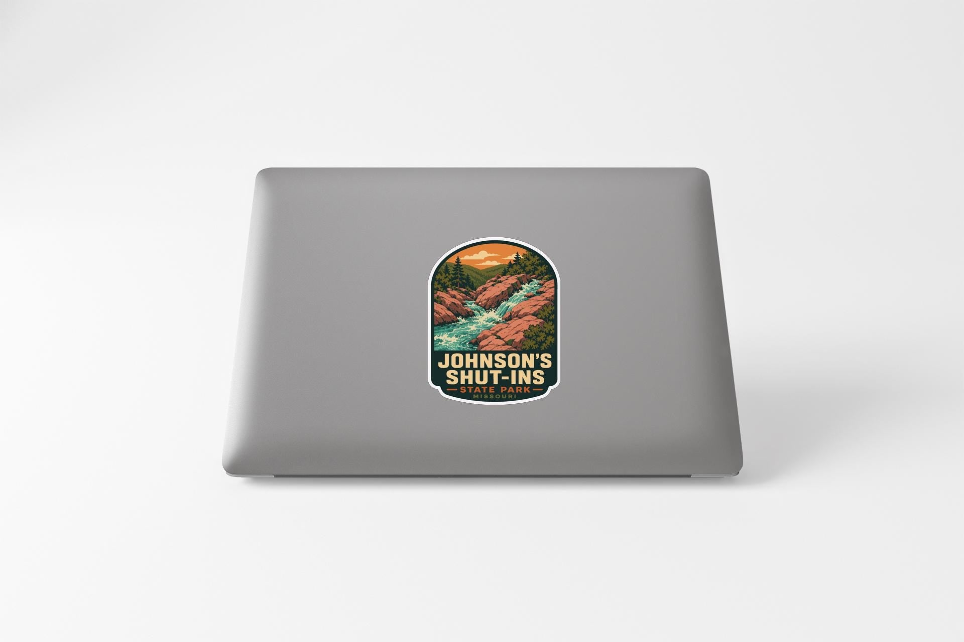 A sticker on the back of a laptop computer with a scenic mountain landscape and the text "Johnson's Shut-Ins" printed on it.