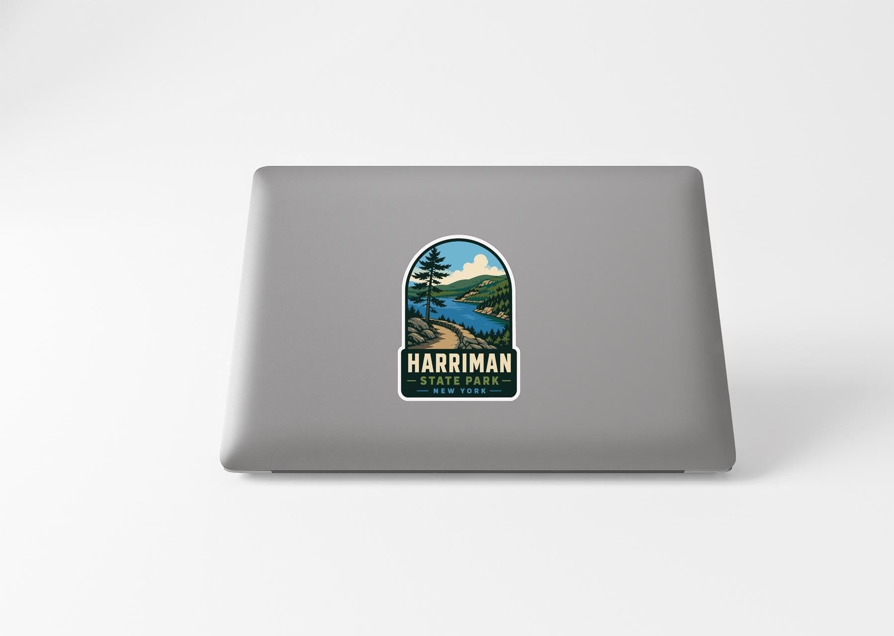 A sticker on the back of a laptop, depicting a scenic landscape with a lake and mountains.