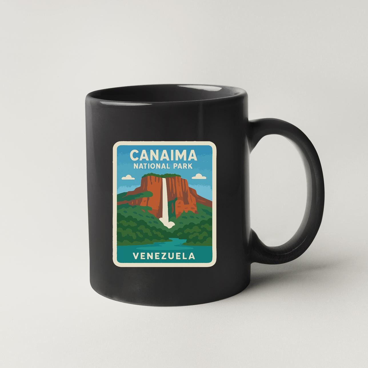 A black coffee mug with a sticker depicting the Canaima National Park in Venezuela.
