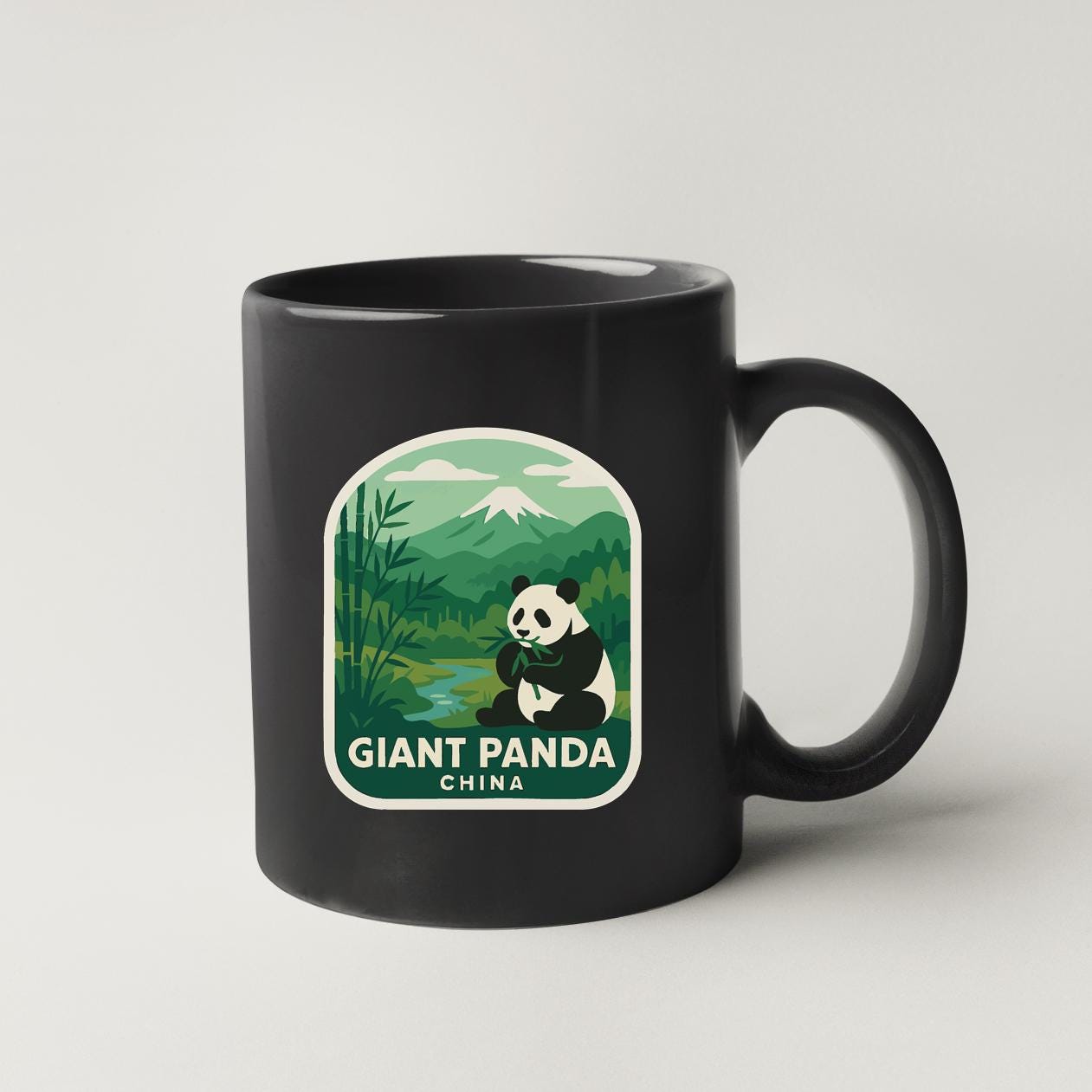 A black coffee mug with a graphic design featuring a panda bear and a landscape with mountains in the background.
