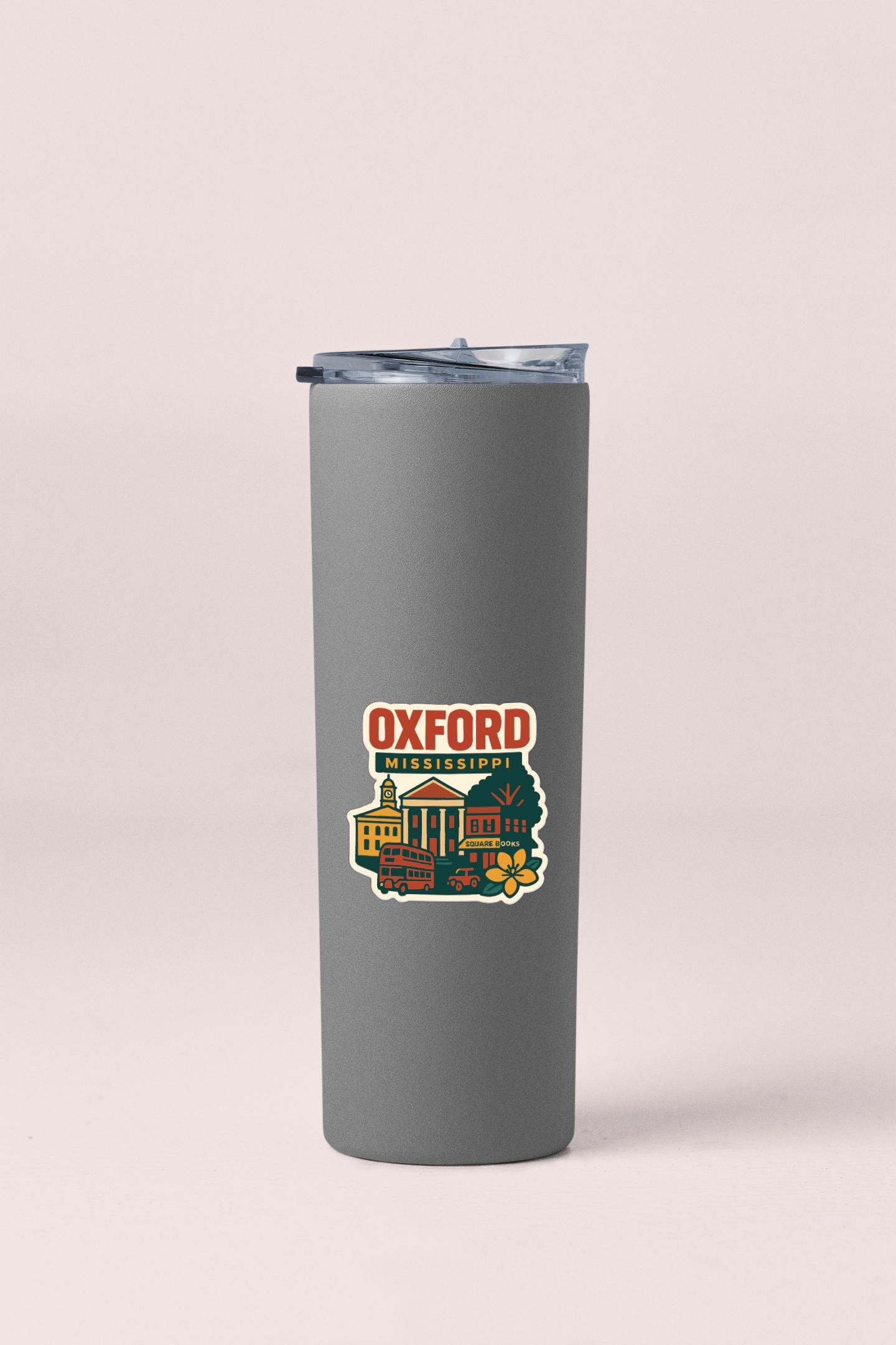 A gray insulated tumbler with a sticker depicting a cityscape and the text "Oxford, Mississippi" printed on it.