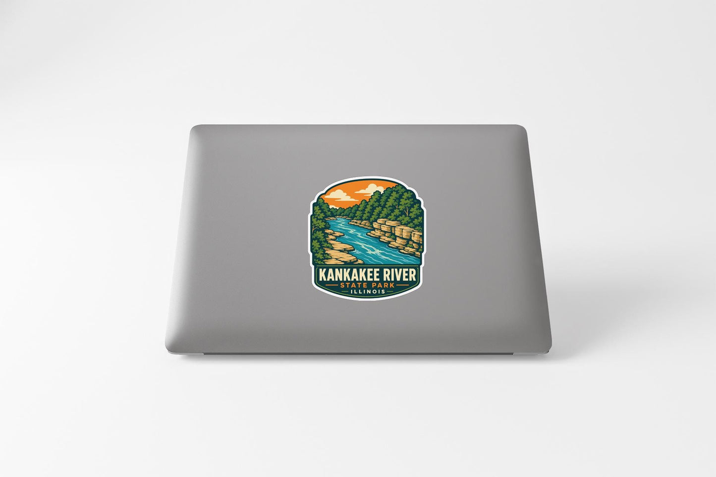 A sticker on the back of a laptop, depicting a scenic landscape with a river and mountains.