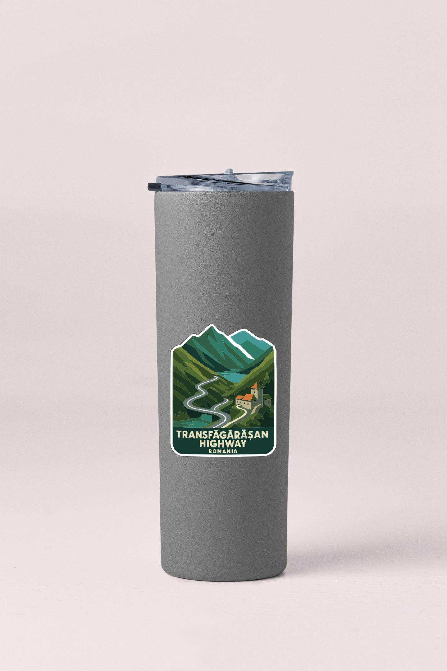 A gray insulated tumbler with a label that says "TRANSFAGARASAN HIGHWAY BOMAIA".
