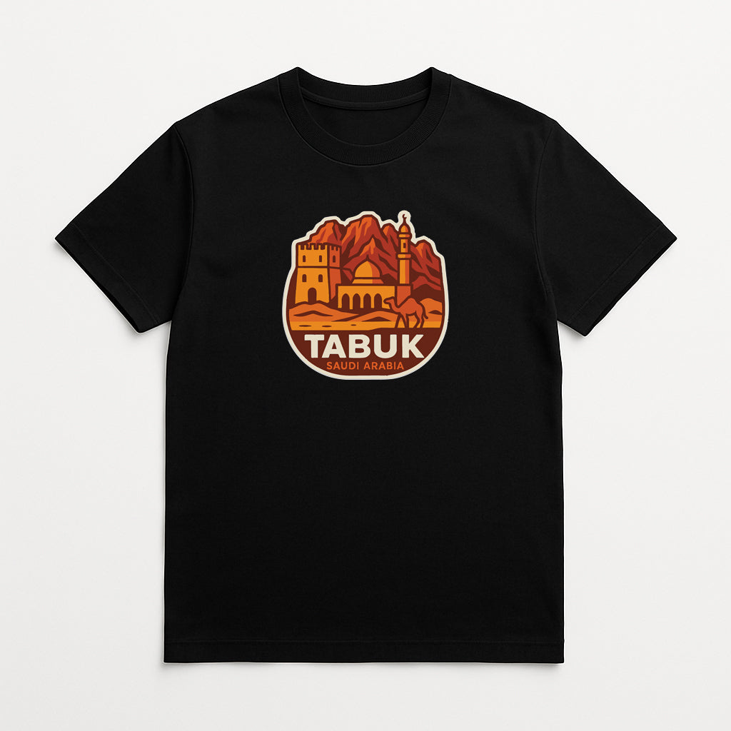 A black t-shirt with a graphic design featuring a castle, mountains, and a camel, along with the text "TABUK SAUDIA ARABIA".