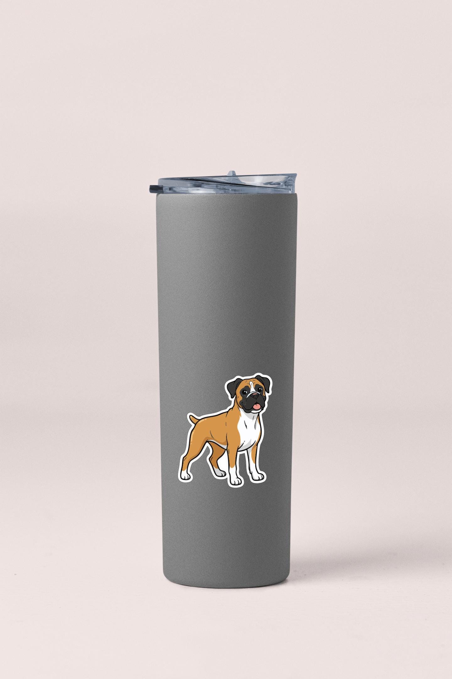 A gray insulated tumbler with a sticker of a brown and white dog on it.