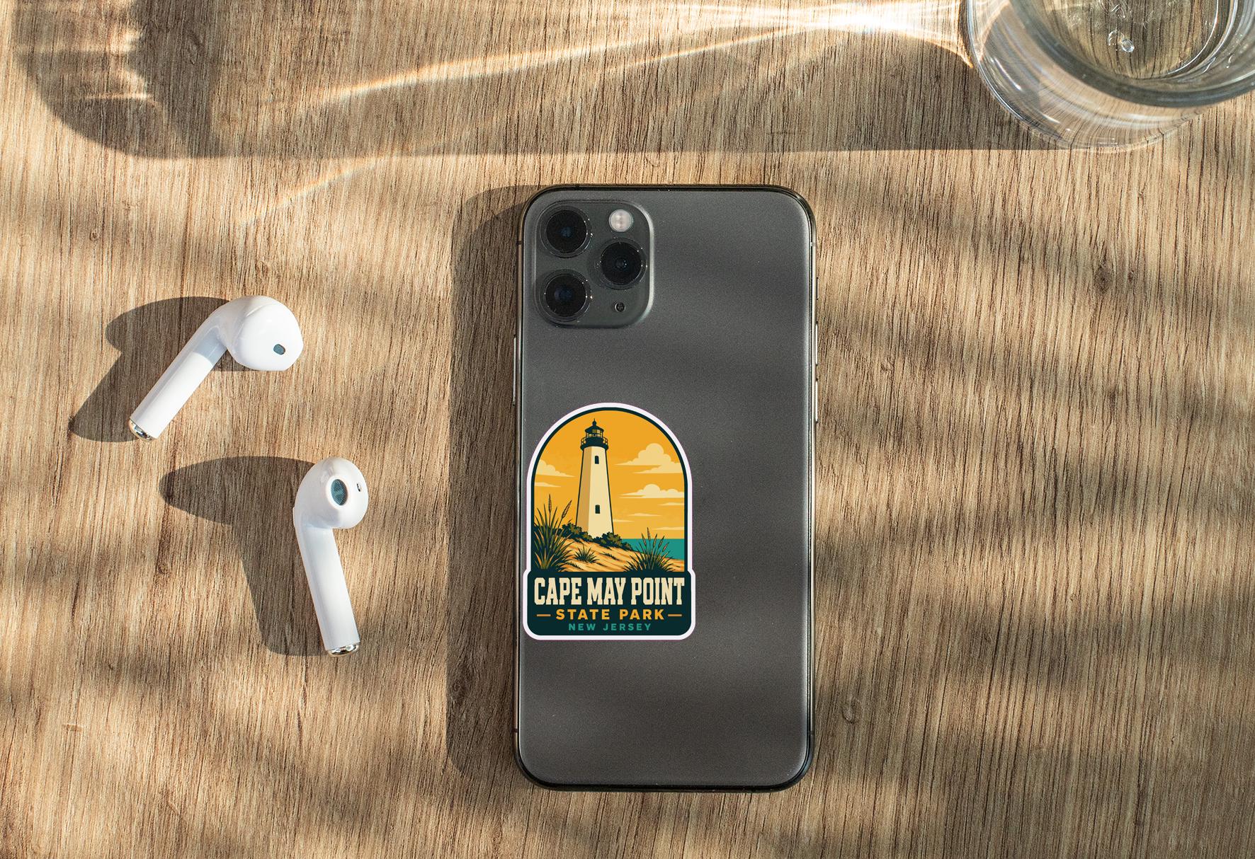 a smartphone with a sticker on the back, placed on a wooden surface alongside a pair of white earbuds and a glass of water.