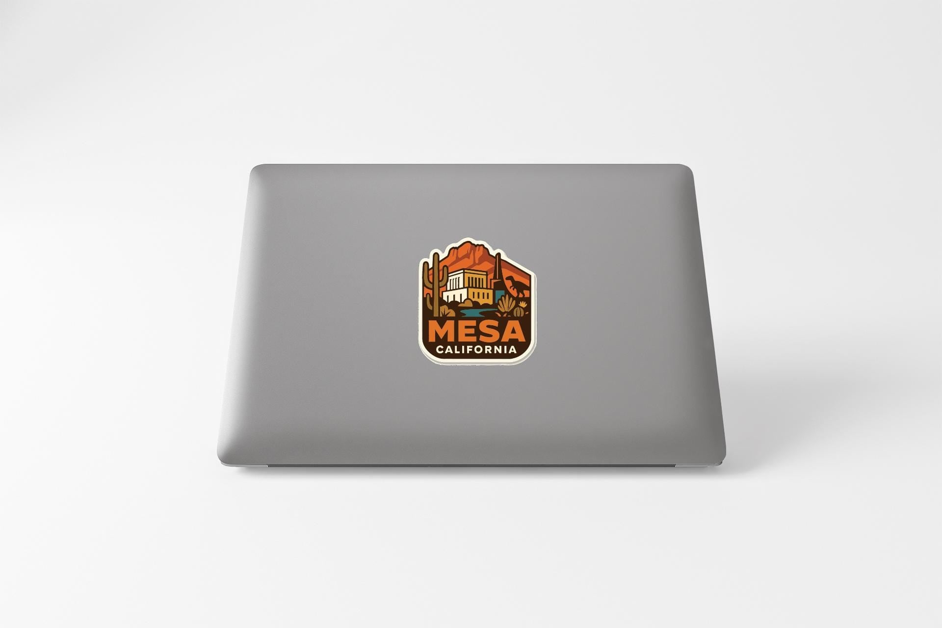 a sticker with the text "MESA CALIFORNIA" on a grey laptop.