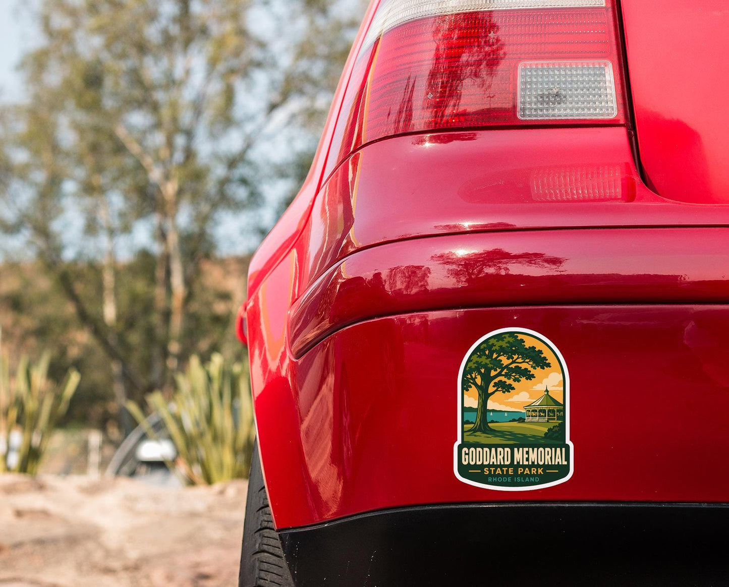 the rear end of a red car with a sticker on the back window that says "Godard Memorial State Park".