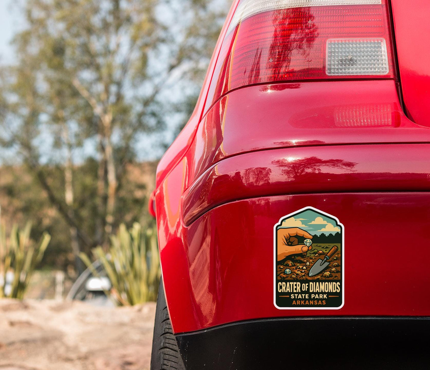 the rear end of a red car with a sticker on the trunk that says "Crater of Diamonds State Park Arkansas".
