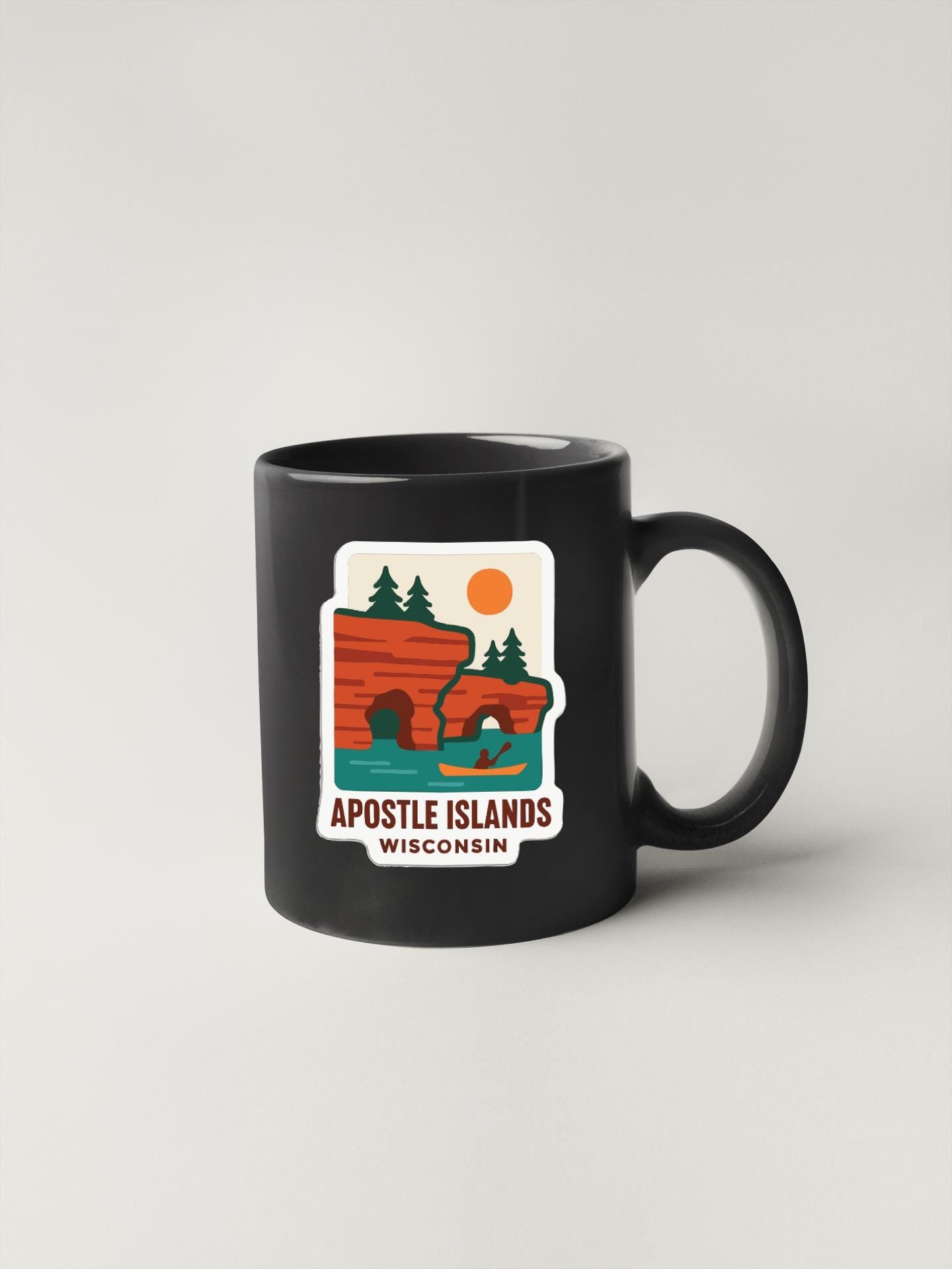A black coffee mug with a graphic design depicting the Apostle Islands in Wisconsin.