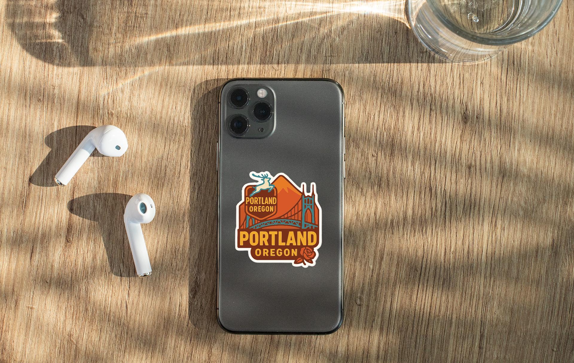 a smartphone with a sticker on the back, placed on a wooden surface alongside a pair of white earbuds and a glass of water.