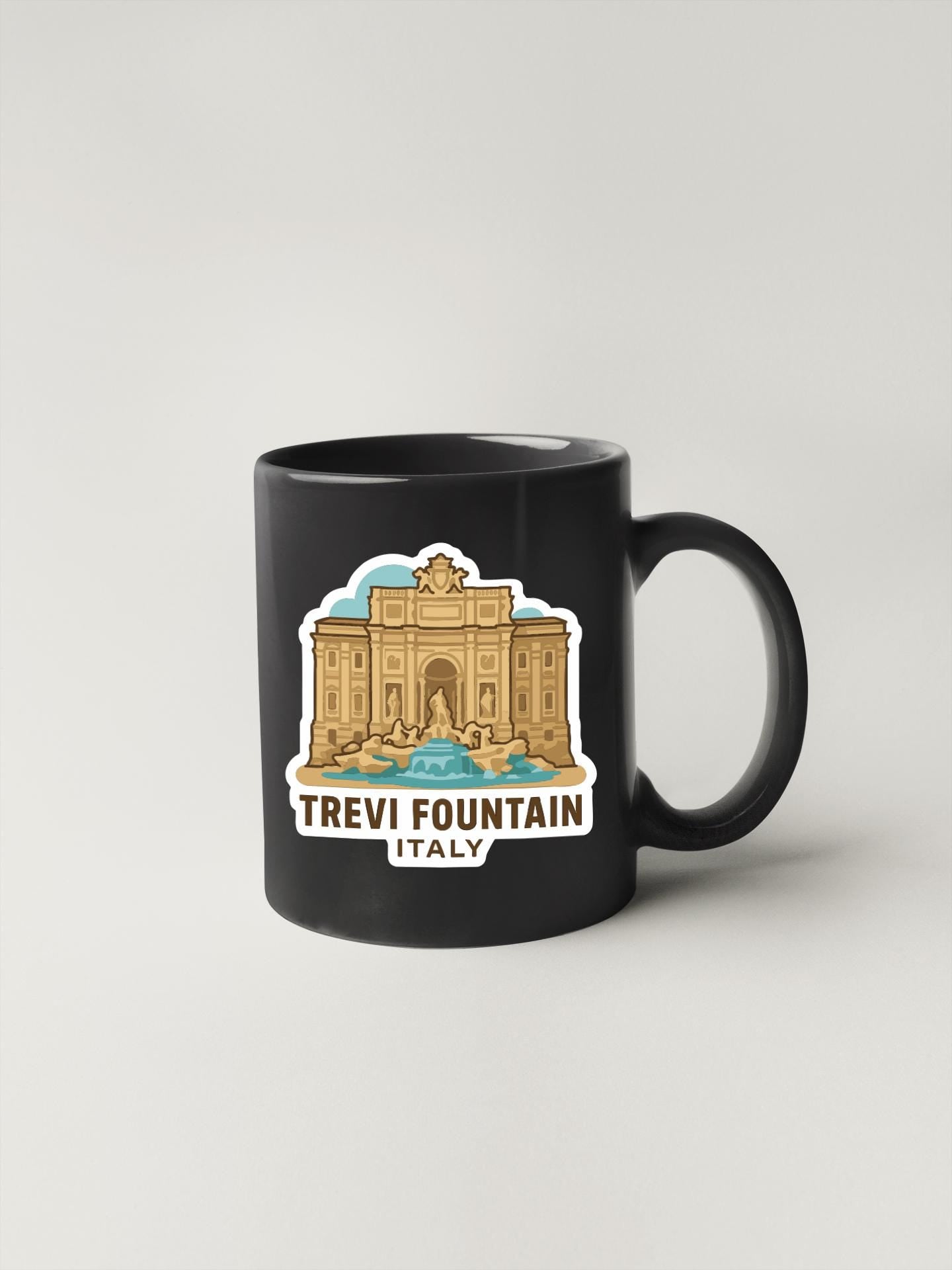 A black coffee mug with a sticker depicting the Trevi Fountain in Italy.