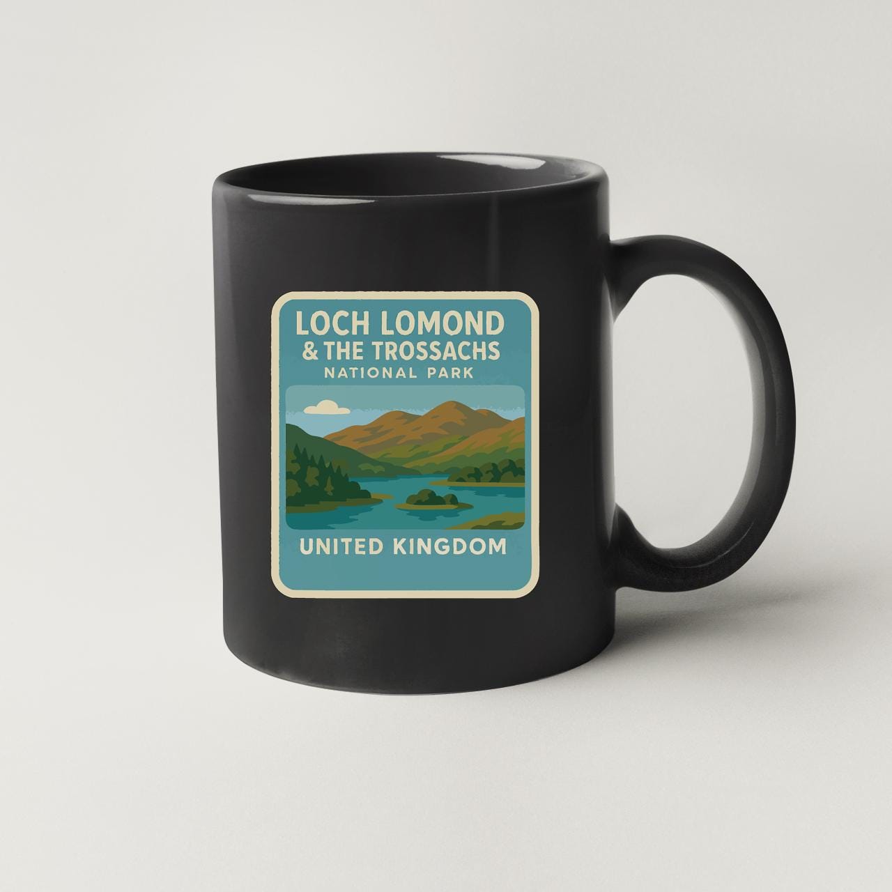 A black coffee mug with a graphic design depicting Loch Lomond and the Trossachs National Park in the United Kingdom.