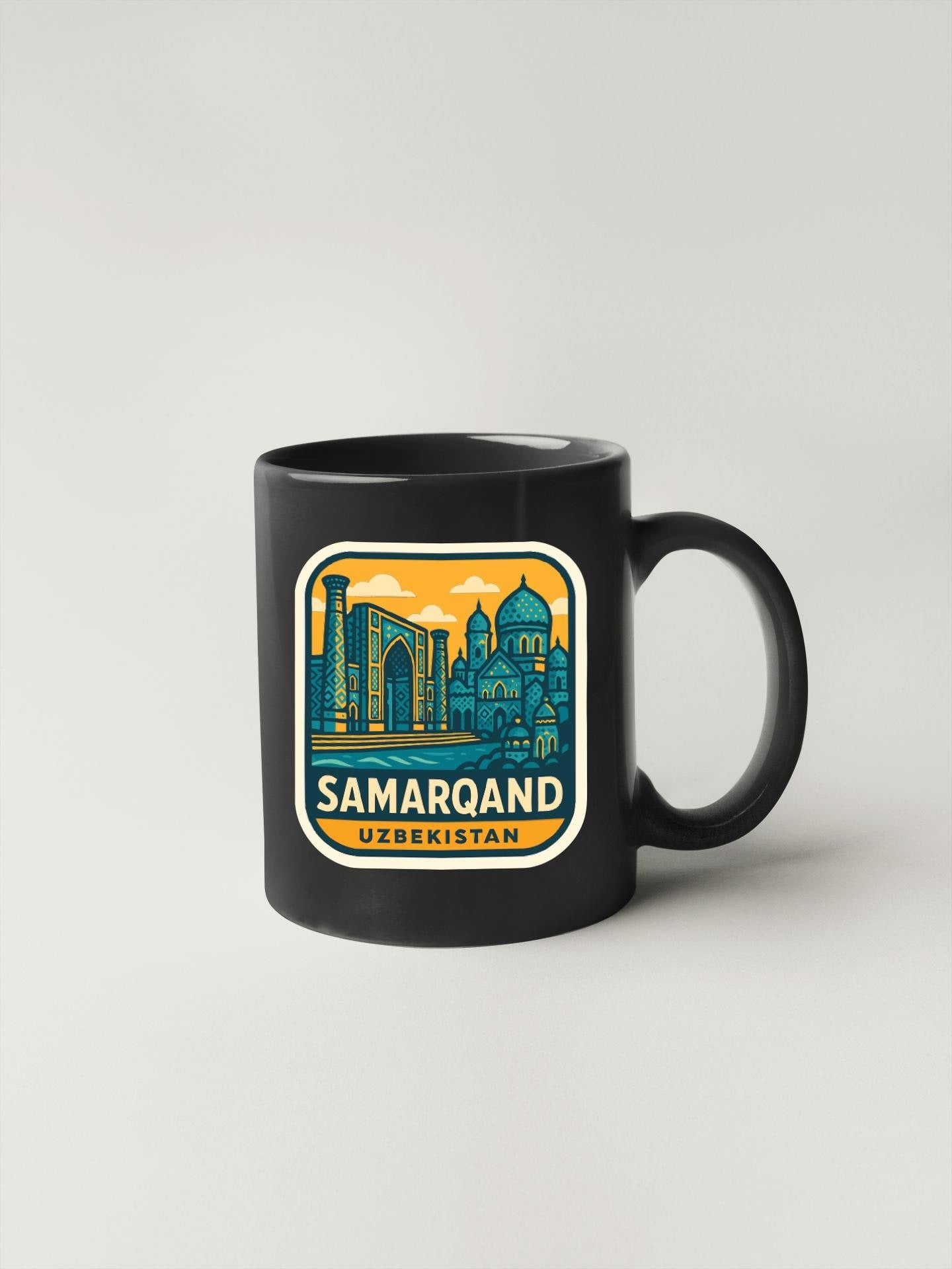 A black coffee mug with a colorful sticker depicting the city of Samarqand, Uzbekistan.