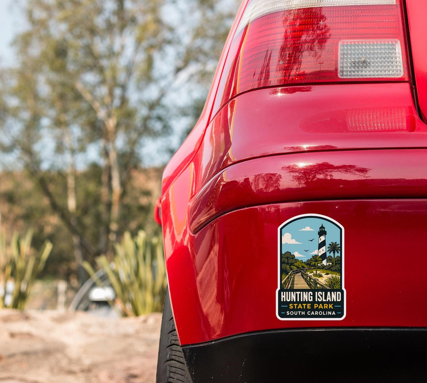 the rear end of a red car with a sticker on the back window that says "Hunting Island State Park South Carolina".