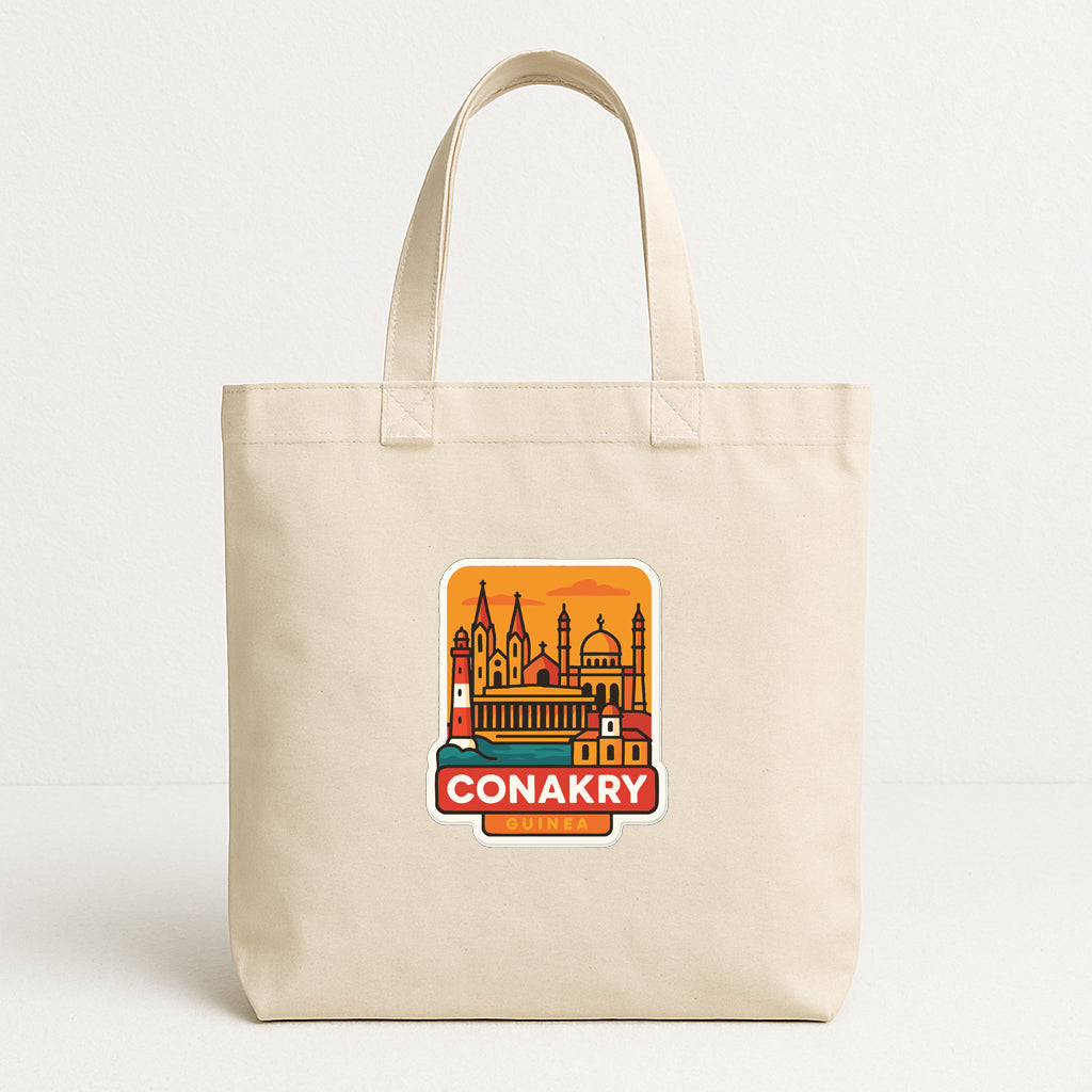 A beige tote bag with a graphic design featuring a city skyline and the text "CONAKRY GUIDE" printed on it.