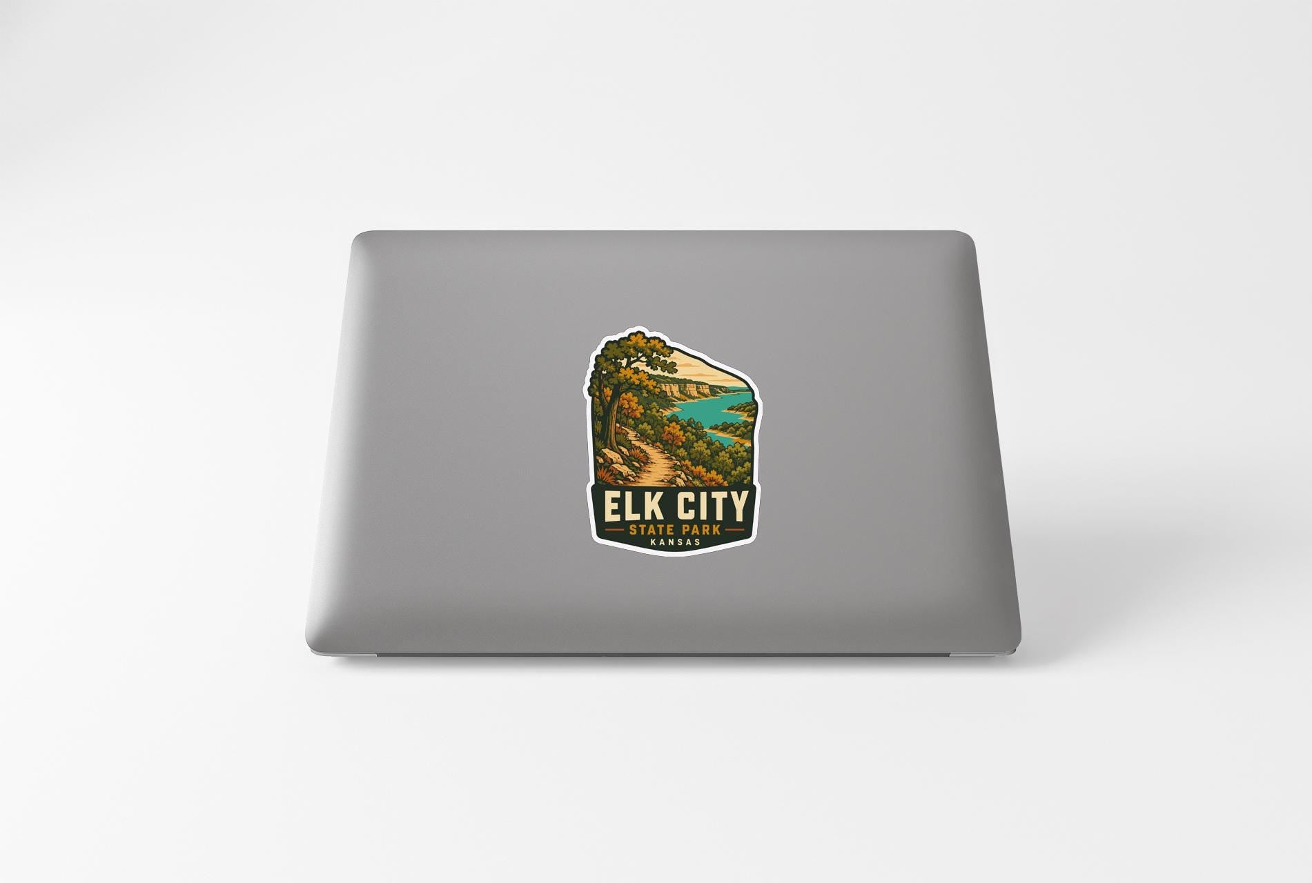 A sticker on the back of a laptop, depicting a scenic landscape with a mountain and a lake.