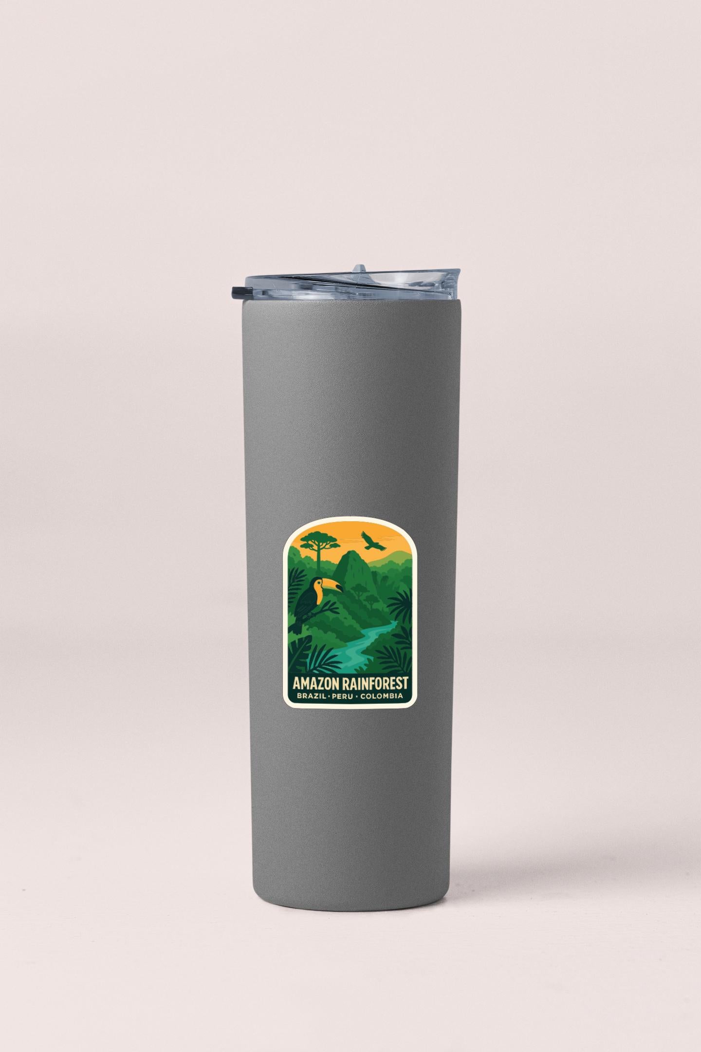 A gray insulated tumbler with a sticker depicting an Amazon rainforest landscape.
