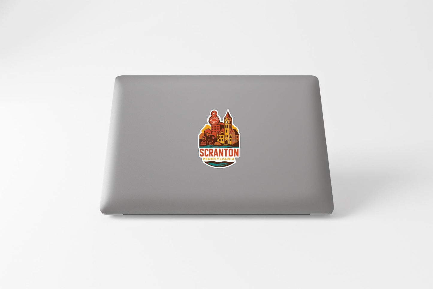 a sticker with a colorful illustration of a building and the text "SCranton" on a grey laptop.