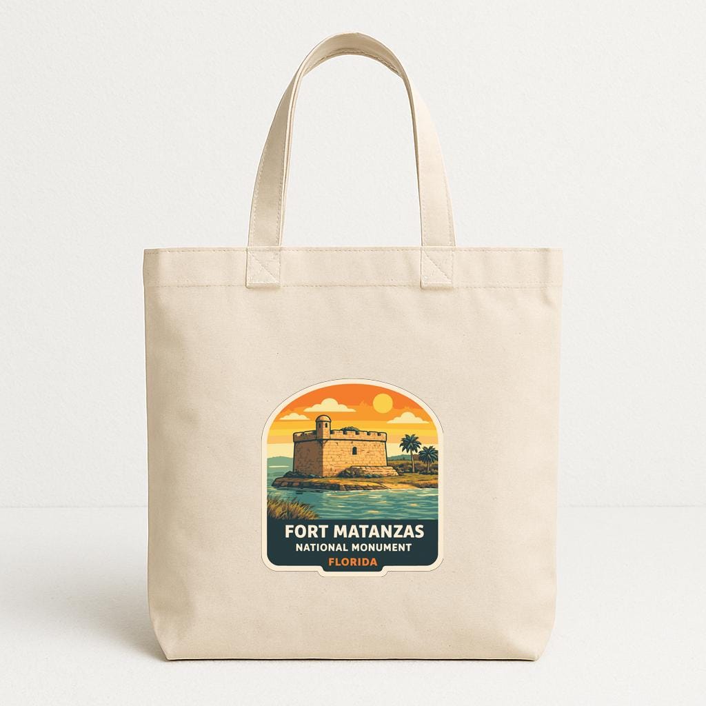 A beige tote bag with a printed design featuring a castle and a sunset over the ocean.