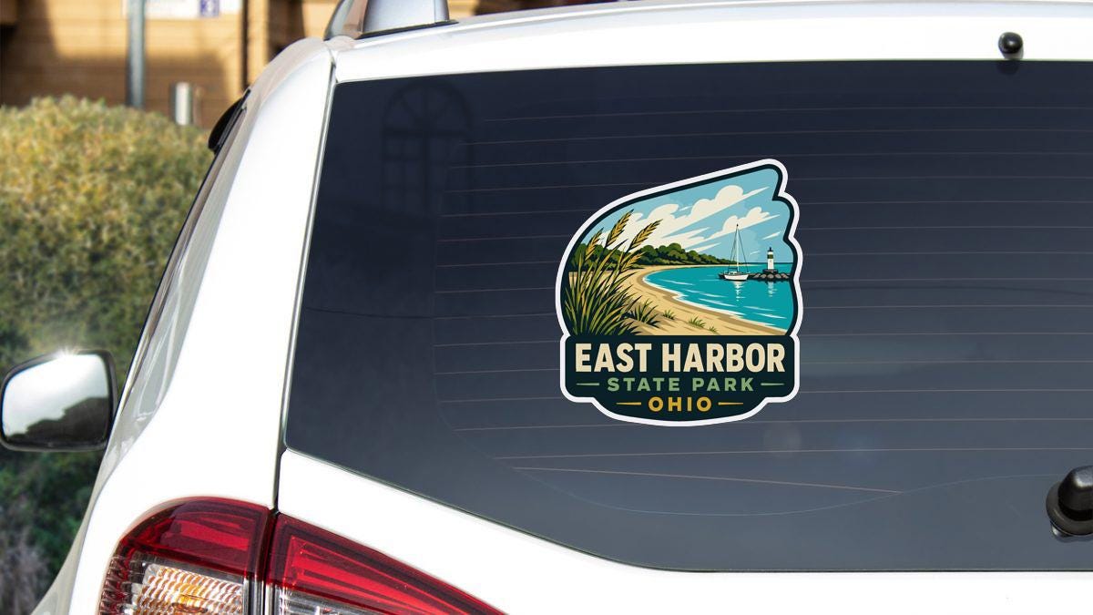 a sticker on the rear window of a white vehicle, depicting a scenic view of East Harbor State Park in Ohio.