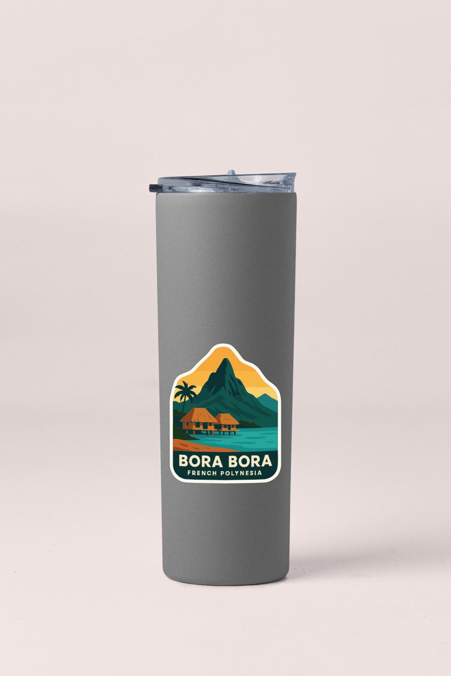 A gray insulated tumbler with a sticker depicting a tropical island landscape.