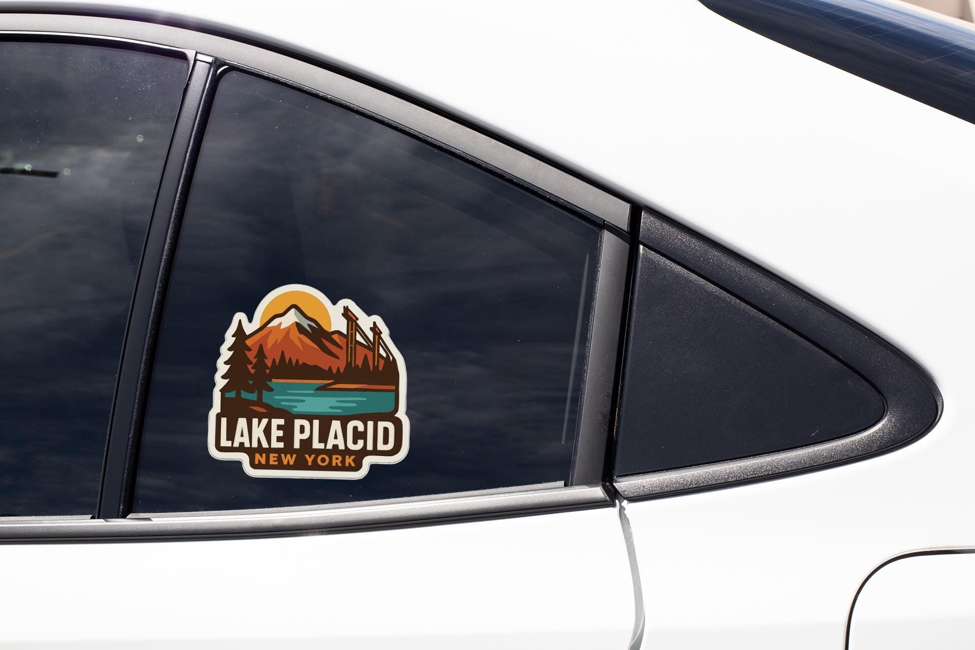 A sticker on the side of a car window that says "Lake Placid New York".