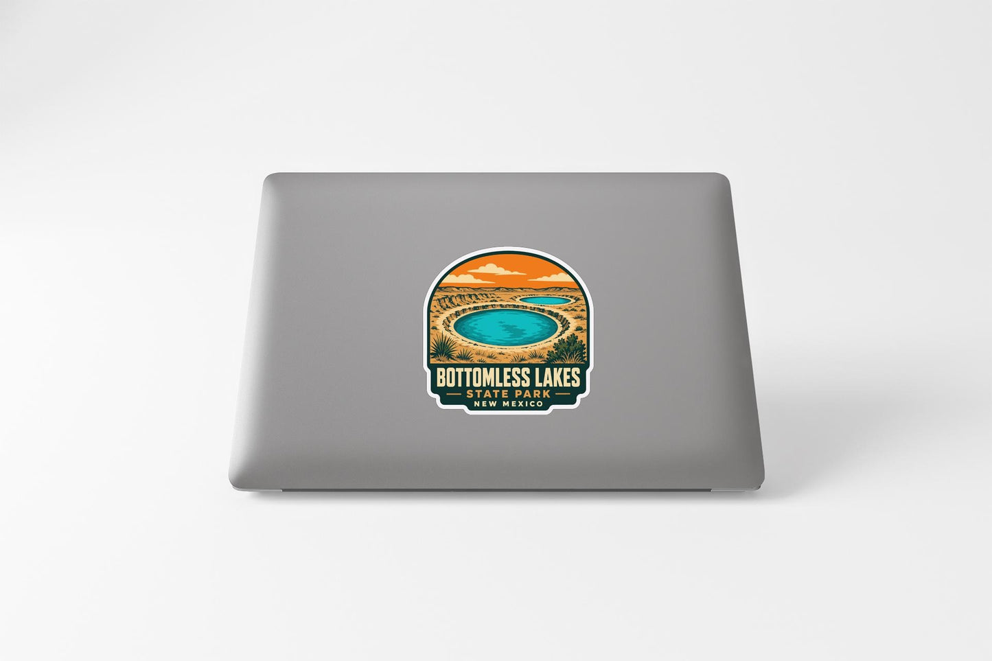 A sticker on the back of a laptop, depicting a scenic landscape with a lake and mountains in the background.