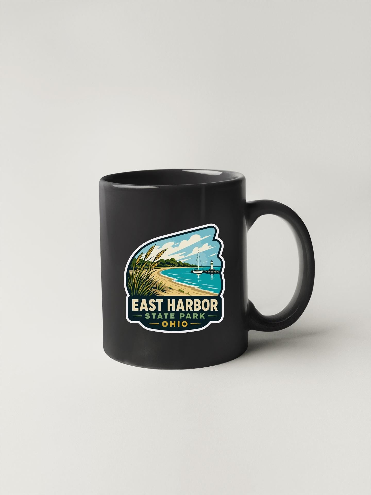 A black coffee mug with a graphic design depicting a beach and ocean, along with the text "EAST HARBOR STATE PARK OHIO".