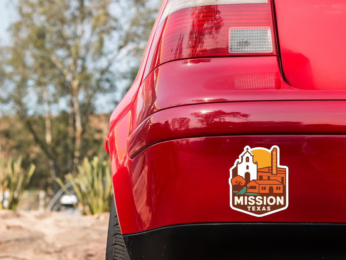 the rear end of a red car with a sticker on the trunk that says "MISSION TEXAS".