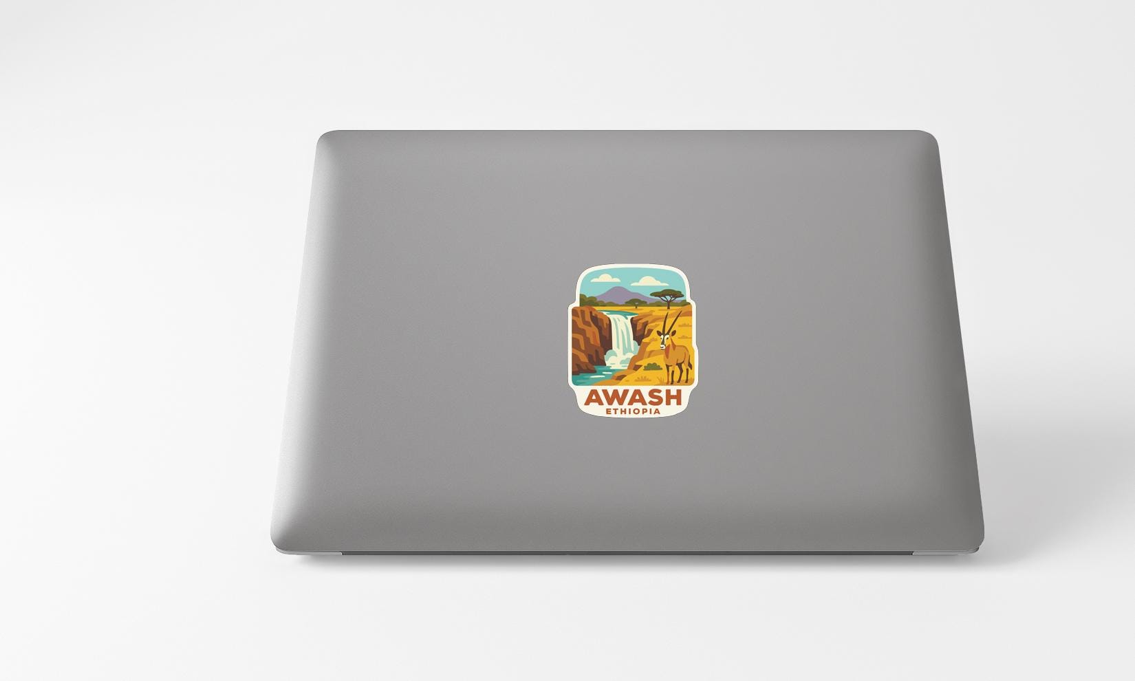 a sticker with a graphic of a waterfall and the word "AWASH" on a laptop.