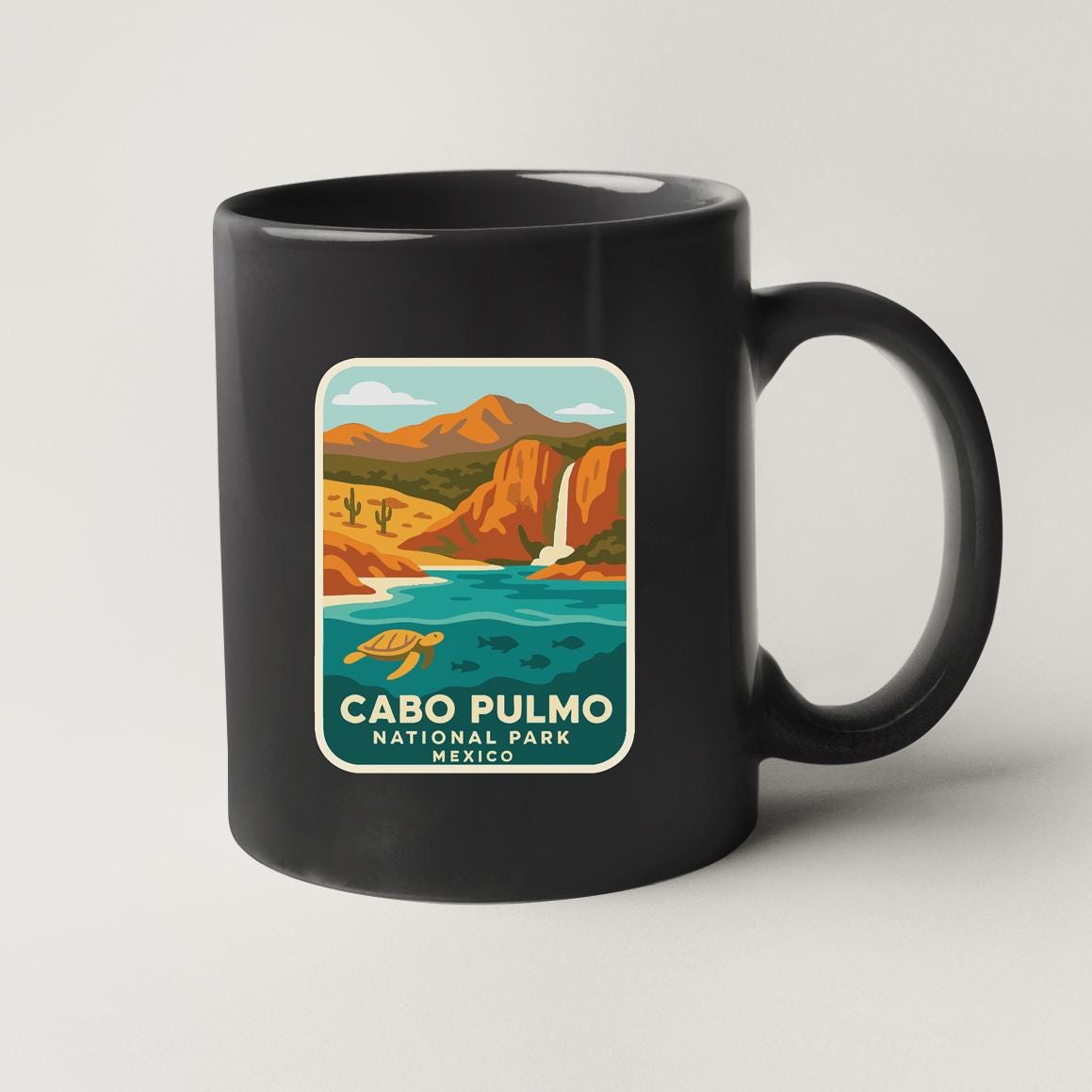 A black coffee mug with a graphic design depicting a scenic landscape of Cabo Pulmo National Park in Mexico.