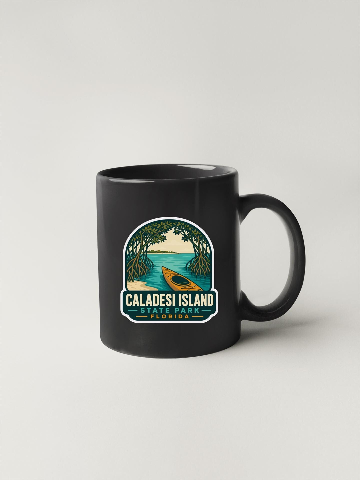 A black coffee mug with a graphic design depicting a canoe on a tropical island, surrounded by palm trees and a blue sky.