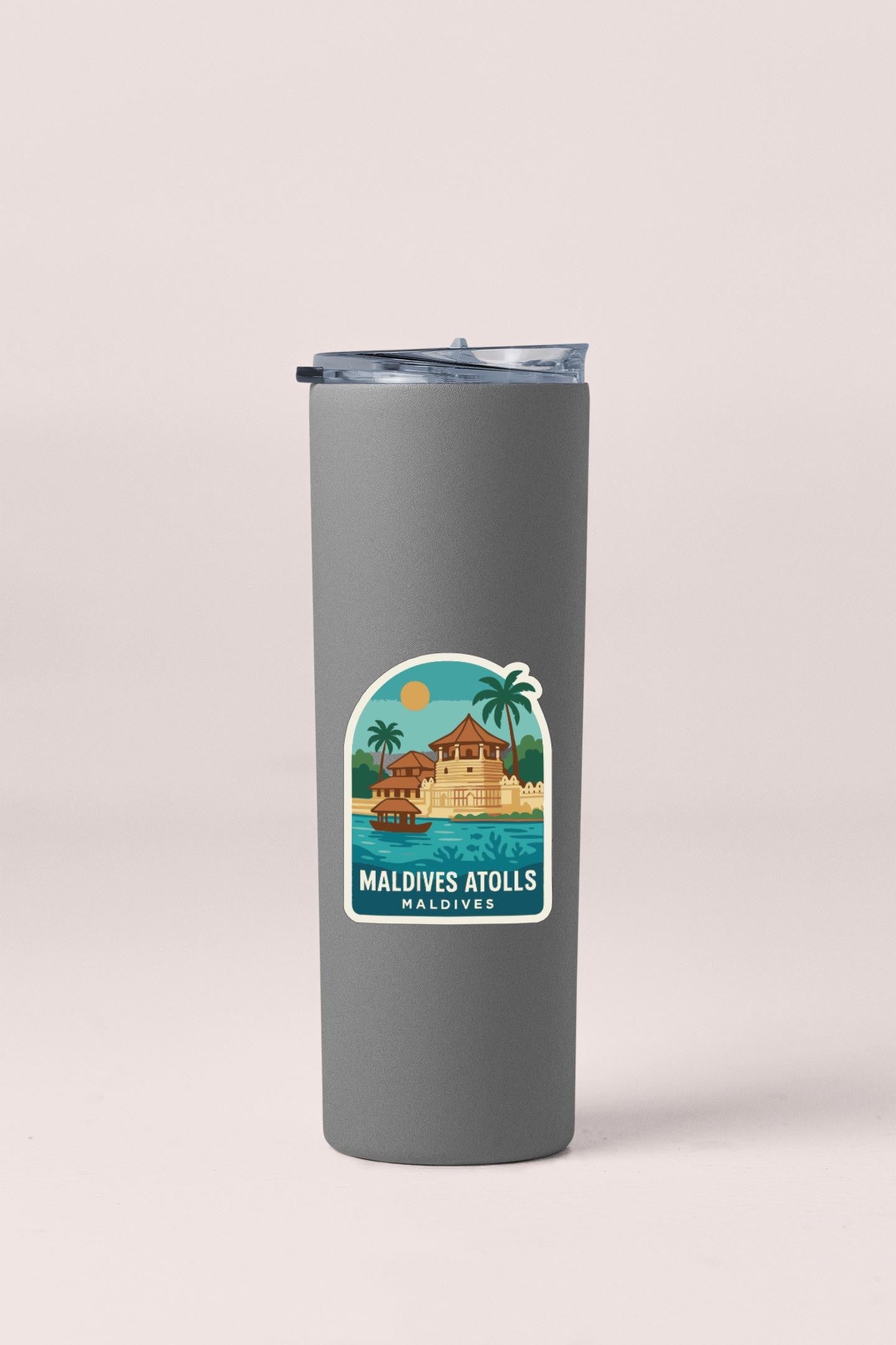A gray insulated tumbler with a sticker depicting a tropical island and palm trees, along with the text "Maldives Atolls Maldives".