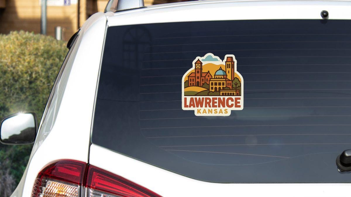 A sticker on the rear window of a white vehicle, depicting a cityscape with buildings and a clock tower.