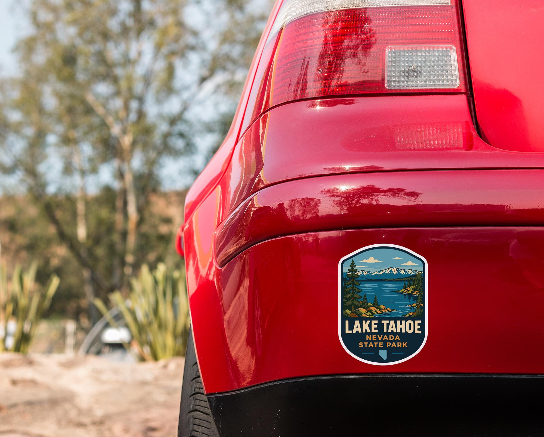 the rear end of a red car with a Lake Tahoe State Park sticker on the trunk.