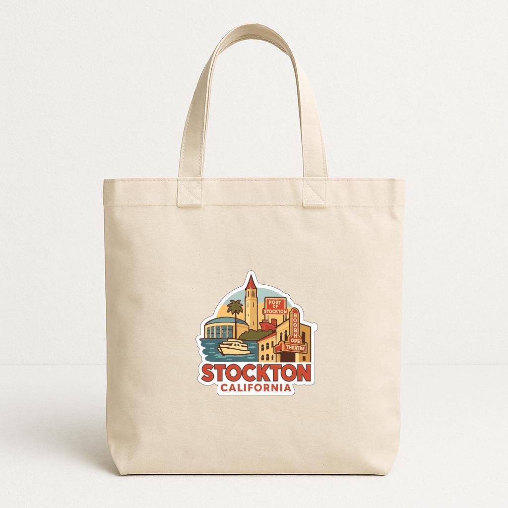 A beige tote bag with a printed design depicting a cityscape and the text "STOCKTON, CALIFORNIA" printed on it.