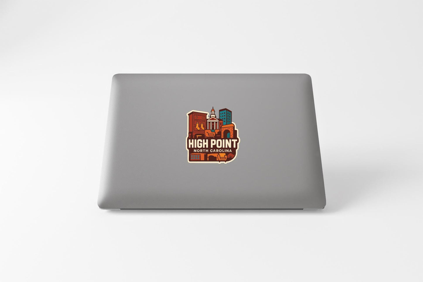 a sticker with a stylized illustration of a cityscape on the back of a laptop.
