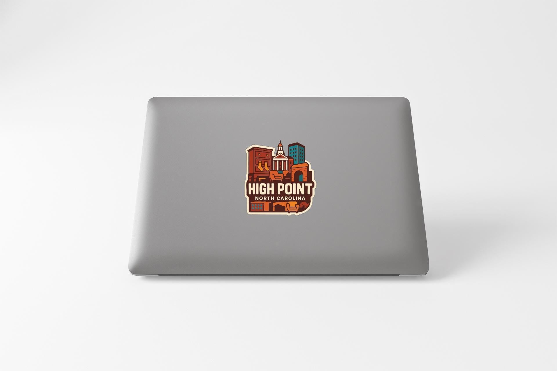 a sticker with a stylized illustration of a cityscape on the back of a laptop.